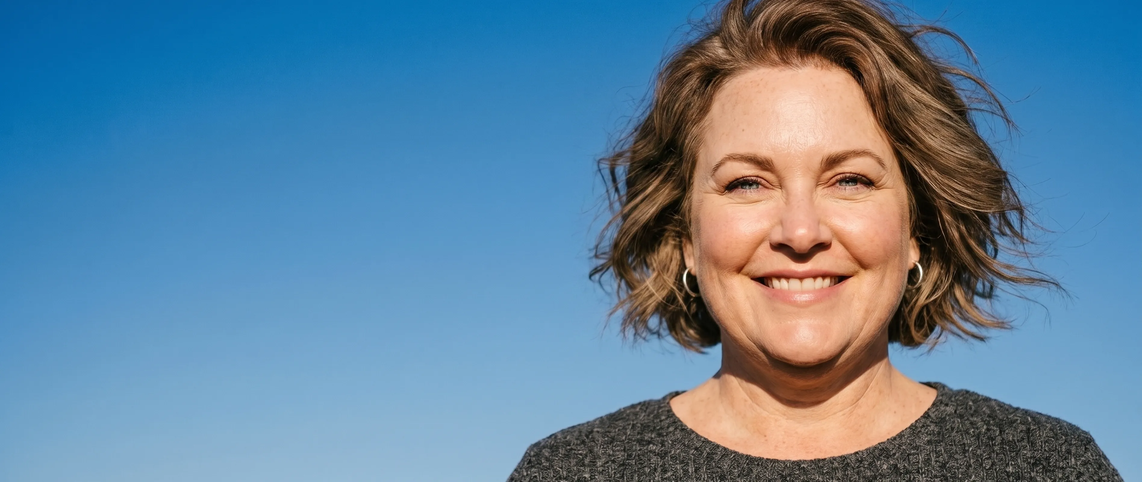 Lächelnde Frau vor blauem Himmel, die sich mit Everywoman um ihre Gesundheit kümmert