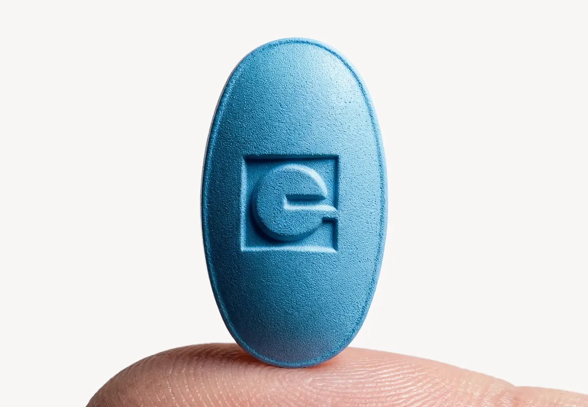 Blaue EVERYMAN-Tablette mit eingeprägtem Logo auf einer Fingerspitze
