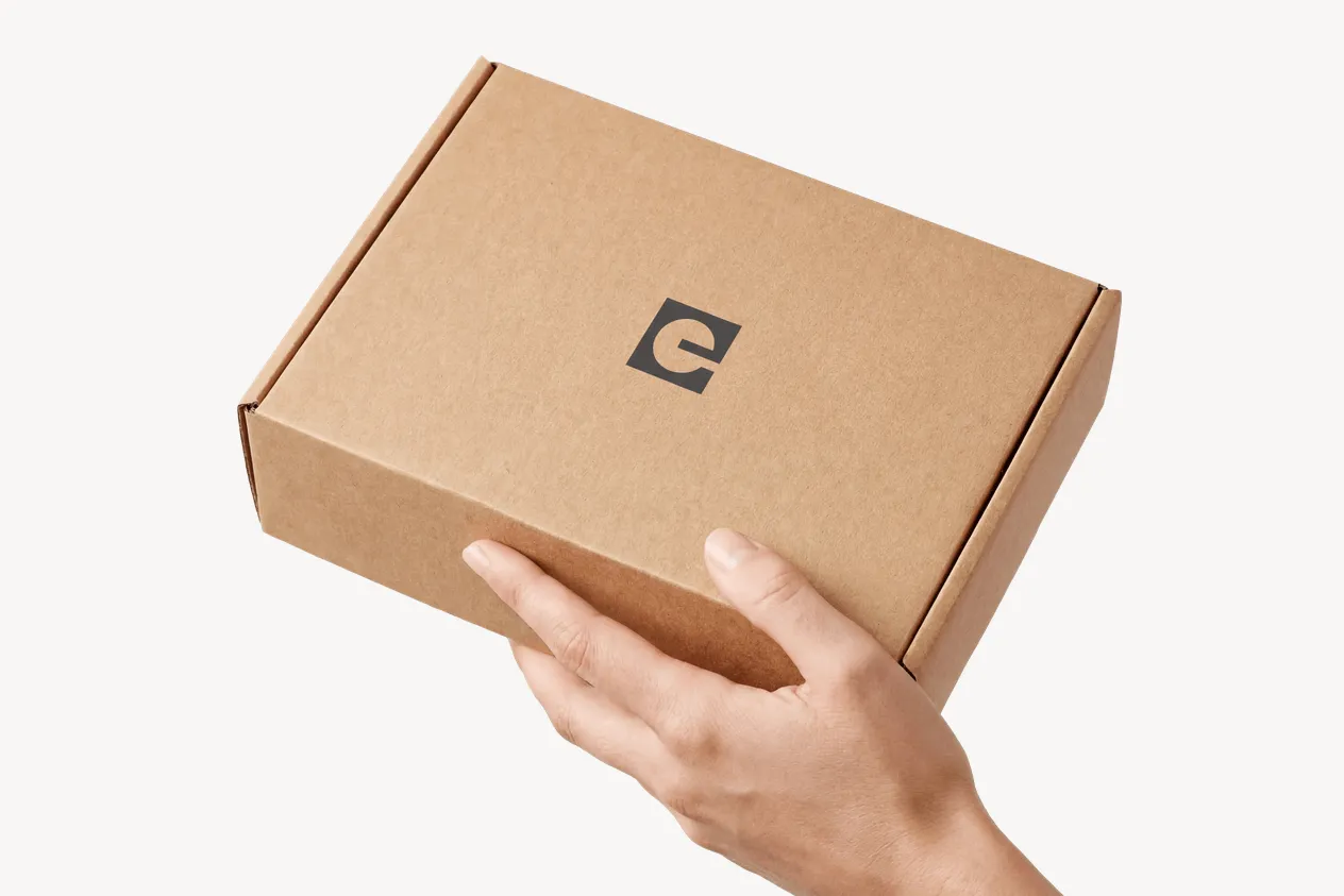Hand mit einem verschlossenen Everywoman-Versandkarton
